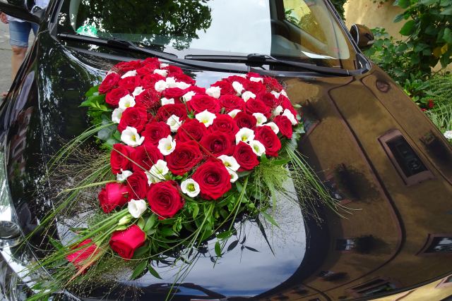 Herz mit roten Rosen und weißen Blumen auf Brautauto